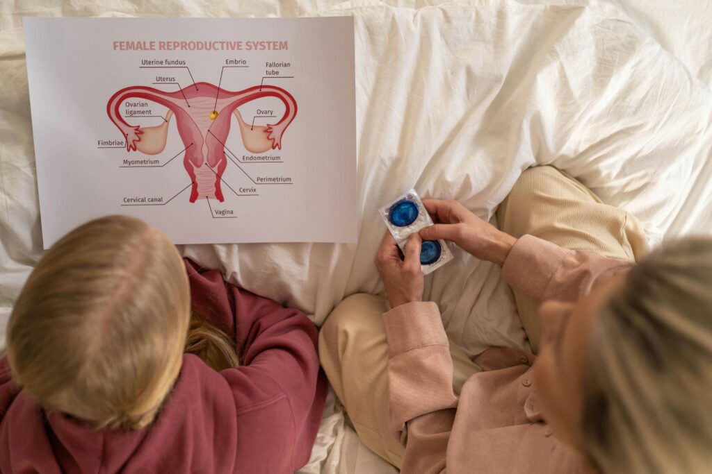 A parent sitting with their teen going over sex education. They are looking at a uterus and the parent is holding condoms.