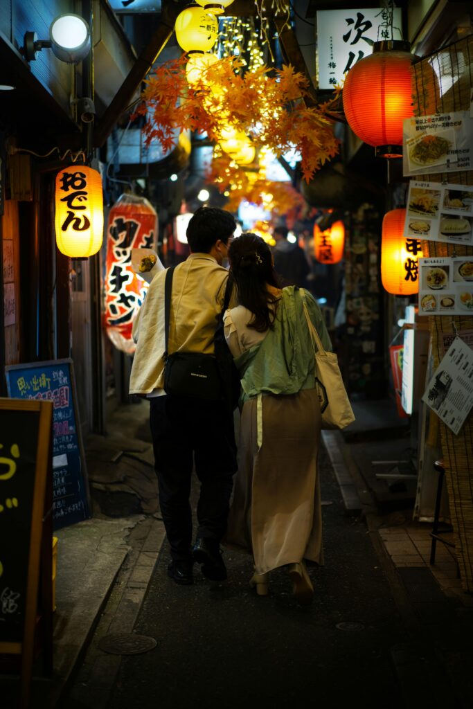 A young couple in japan are walking down a japanese styled alley.