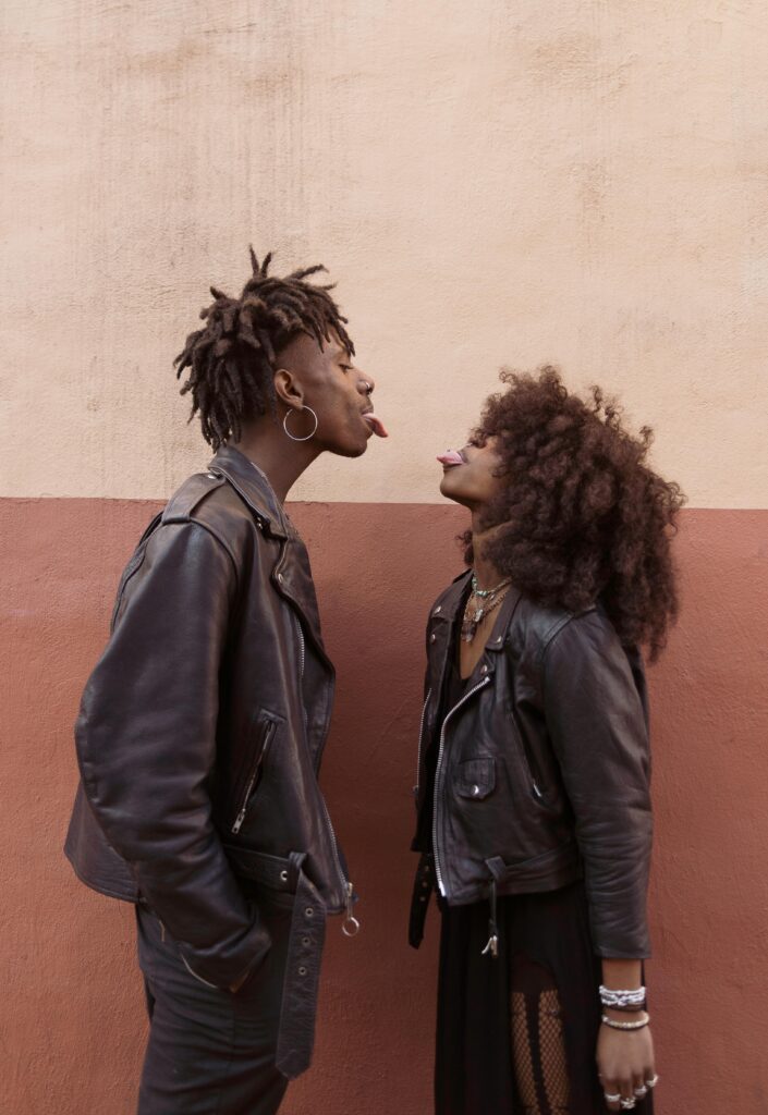 A diverse couple teasing each other by sticking their tongues out.
