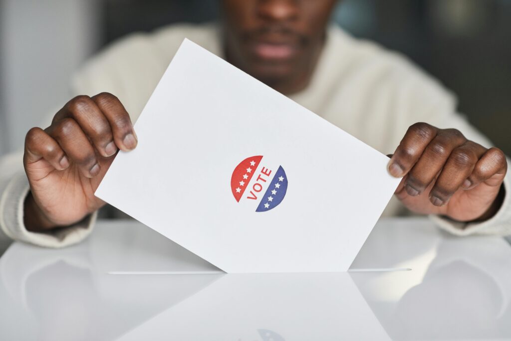 young black man placing a voting ballot into a voting box.
